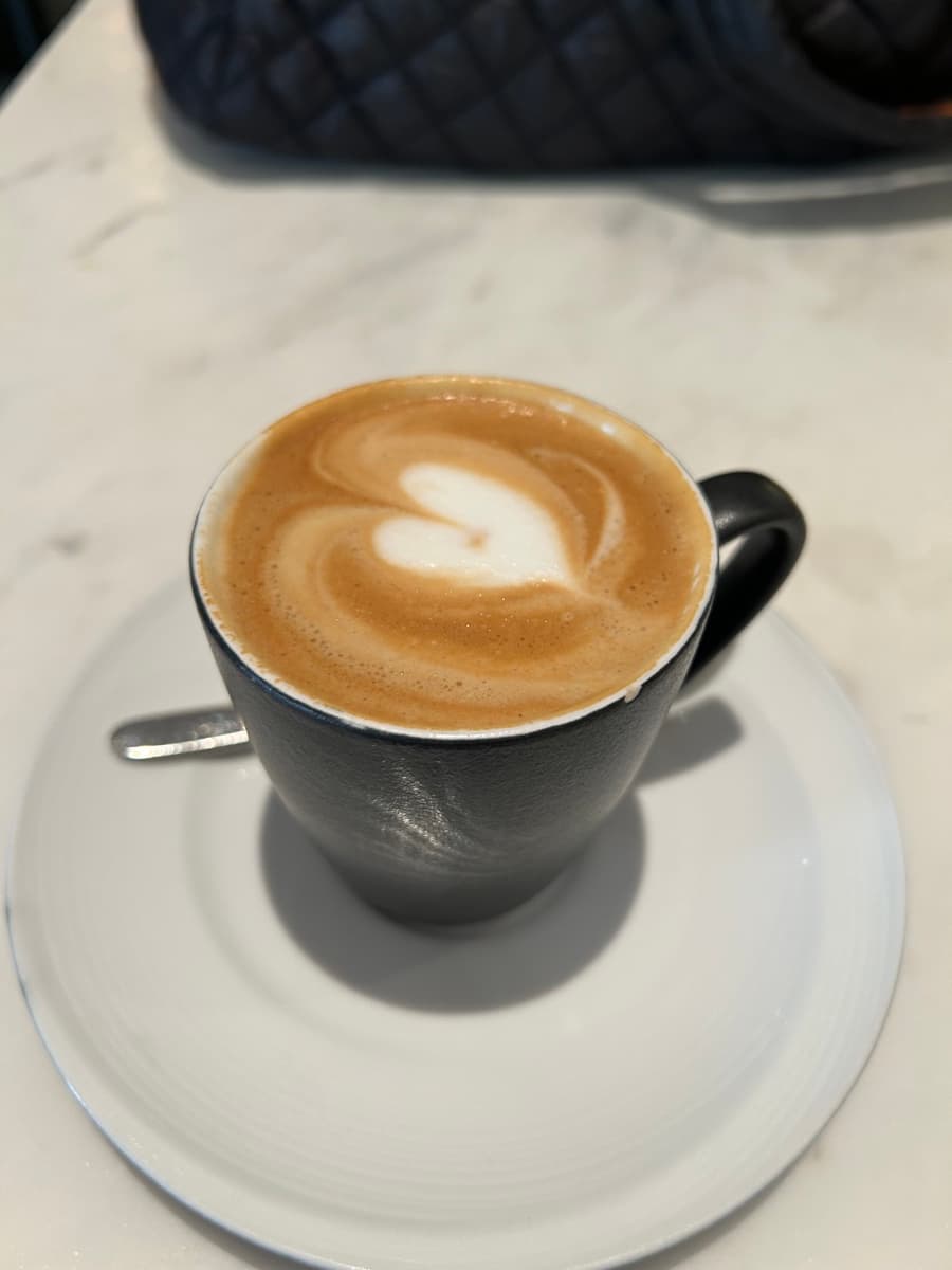 Latte with leaf art on a sunlit wooden table