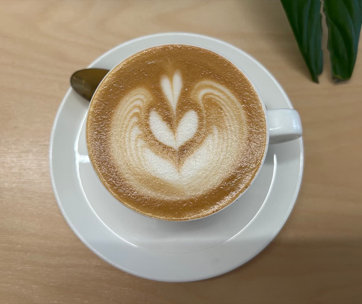 Cortado in a dark ceramic cup on marble
